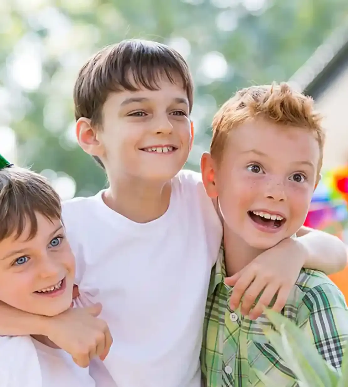 Drei Jungen feiern einen Geburtstag. Alle sind am lachen und im Hintergrund ist Dekoration zu erkennen.