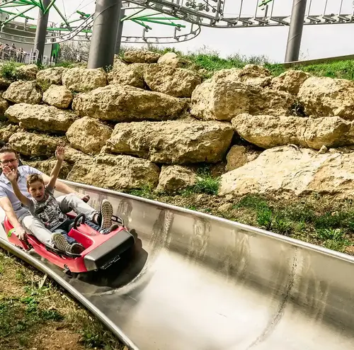 Ein Vater und sein Kind fahren rasant die Sommerrodelbahn der Wiegand Erlebnisberge hinunter. Der Betreiber von Sommerrodelbahnen sorgt für actionreichen Freizeitspaß in natürlicher Umgebung