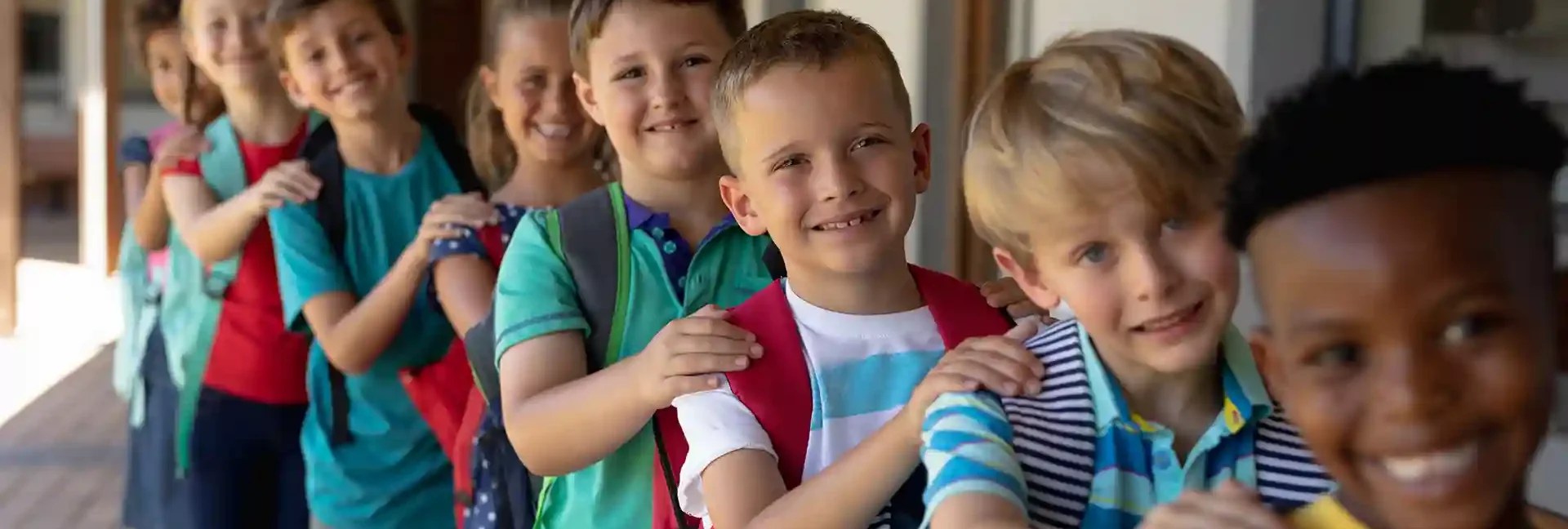 Eine Gruppe mit Kindern ist in einer Reihe aufgestellt. Sie sind alle am lachen und halten sich gegenseitig an den Schultern.