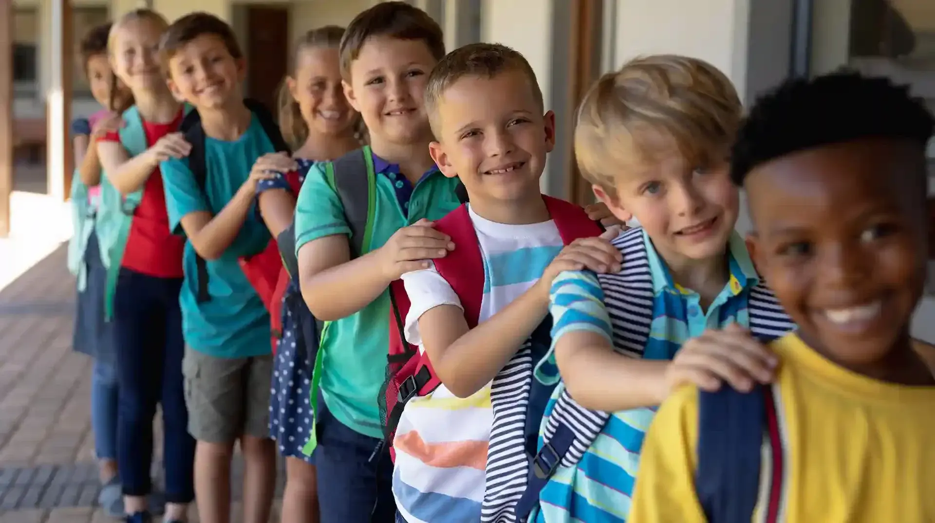 Eine Gruppe mit Kindern ist in einer Reihe aufgestellt. Sie sind alle am lachen und halten sich gegenseitig an den Schultern.